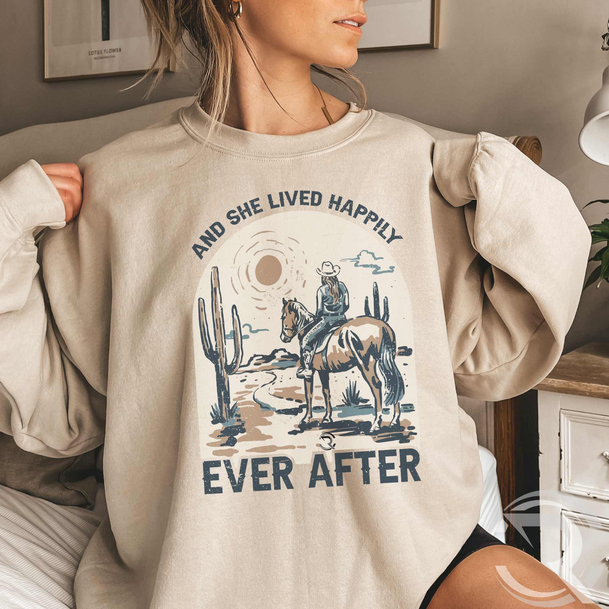 woman sitting on sofa and wearing an oversized tan sweatshirt with western graphic design