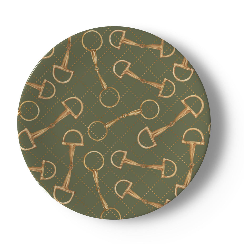 A round decorative plate featuring a repeating pattern of gold horse bits and rings over an olive green background with a subtle dotted diamond grid.