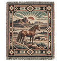 A woven throw blanket with fringe, featuring a western landscape scene with a brown horse in the foreground, another horse in the background, desert mountains, and a sunburst motif, surrounded by a Southwestern geometric border.