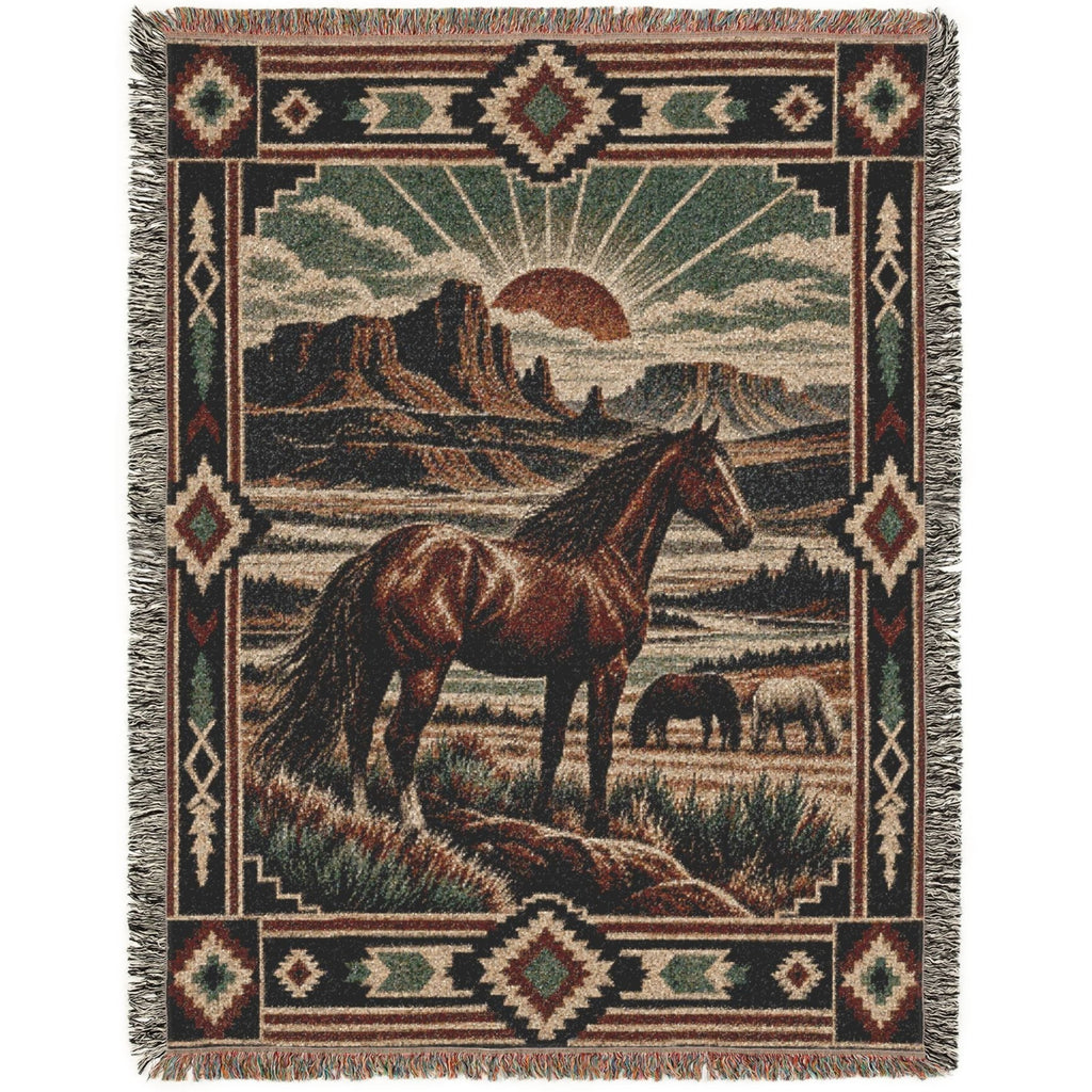 A rectangular woven throw blanket with fringe on all sides, featuring a western landscape scene with a brown horse, a small donkey, mountains, and a sun, surrounded by geometric Southwestern-style borders.