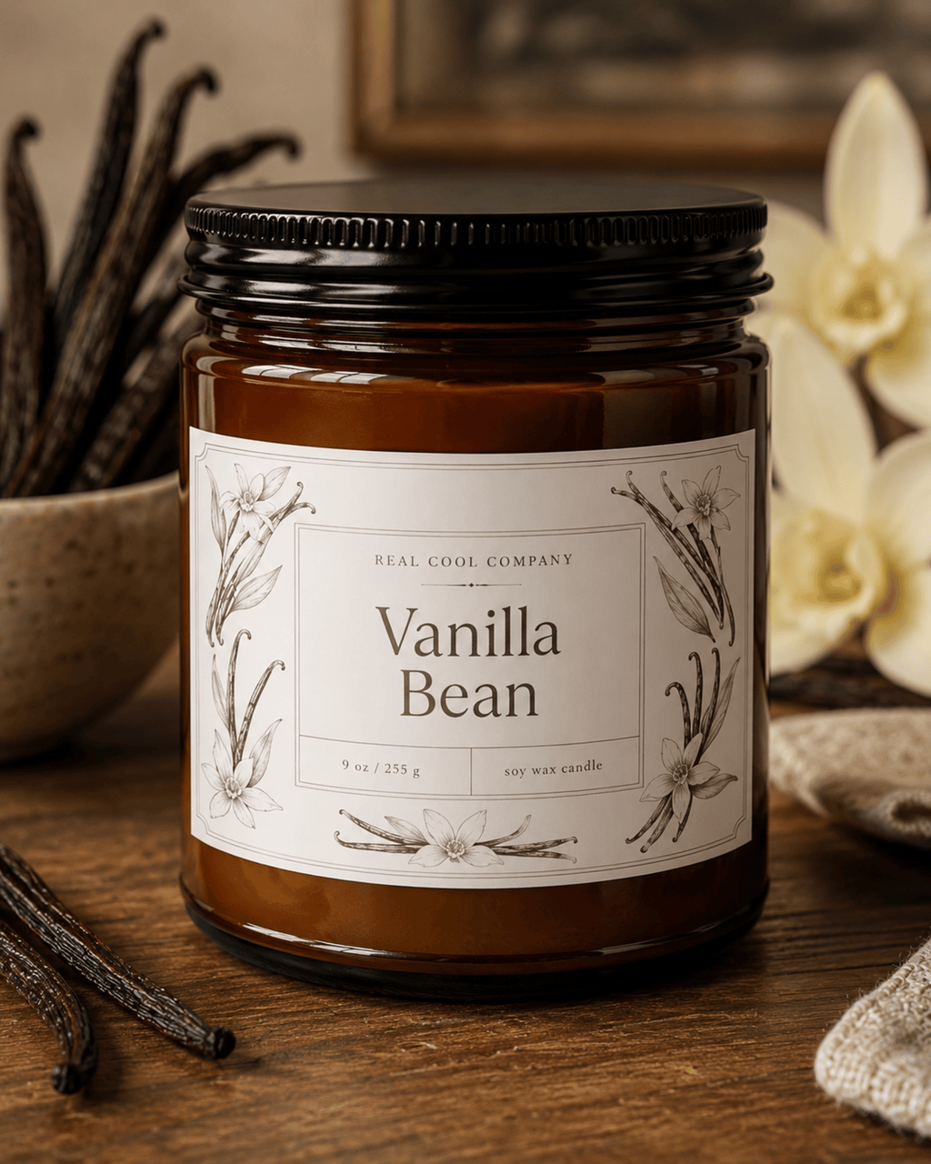 A jar candle labeled 'Vanilla Bean' by Real Cool Company, shown on a rustic wooden surface with vanilla beans and flowers in the background.