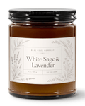 A glass jar candle with amber-brown wax, a black metal lid, and a white label reading 'White Sage & Lavender' by Real Cool Company, shown on a clean white background.