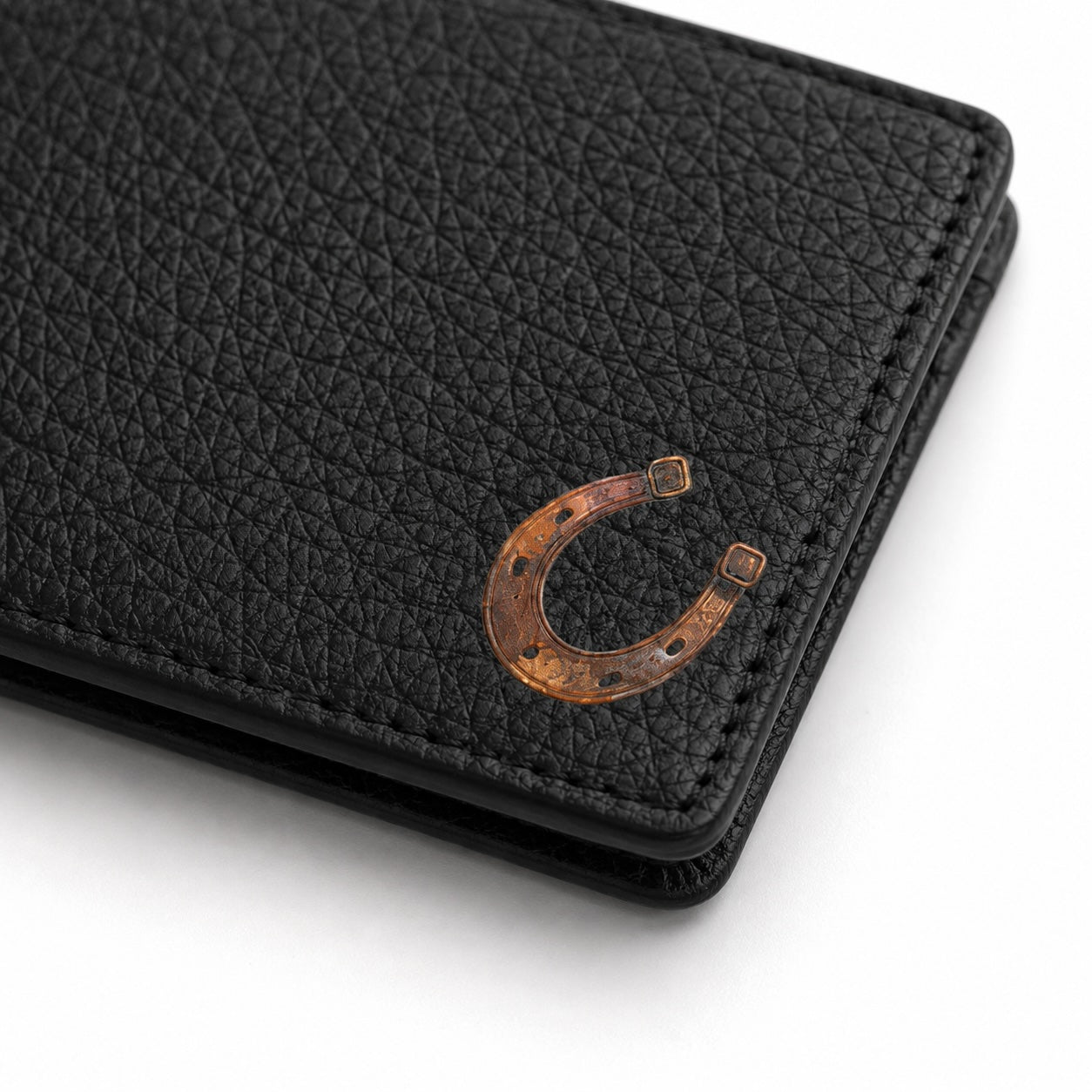 A close-up of a black pebbled leather wallet featuring a metallic bronze horseshoe emblem on the front, set against a clean white background.