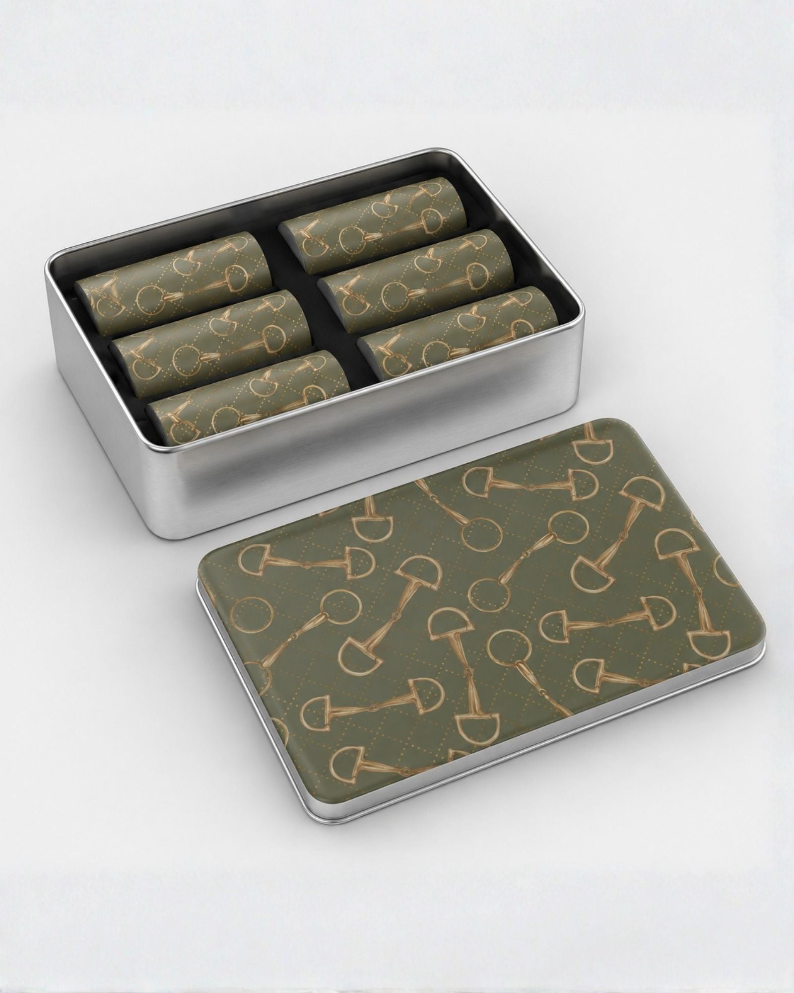A silver metal tin containing six olive green gold horse bit pattern shot glasses, with the lid placed in front showing an olive green pattern of gold horse bits. The background is a clean white studio backdrop.