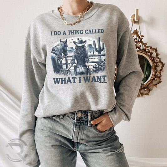 Person wearing a gray sweatshirt with a western graphic and text, standing in a room with a decorative mirror.