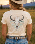 Cowgirl wearing boho bull skull western graphic tee in sunset country field