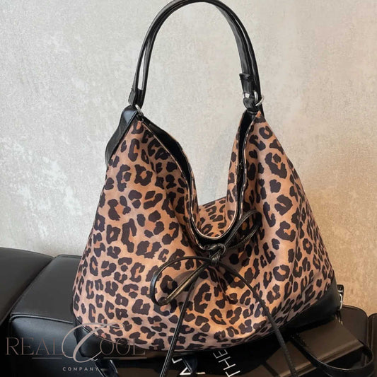 Leopard print handbag with black handles on a neutral background
