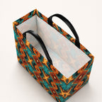 A rectangular premium denim tote with black leather handles, featuring a vibrant geometric pattern in teal, orange, and brown on the exterior, and a light colored lining on the interior.